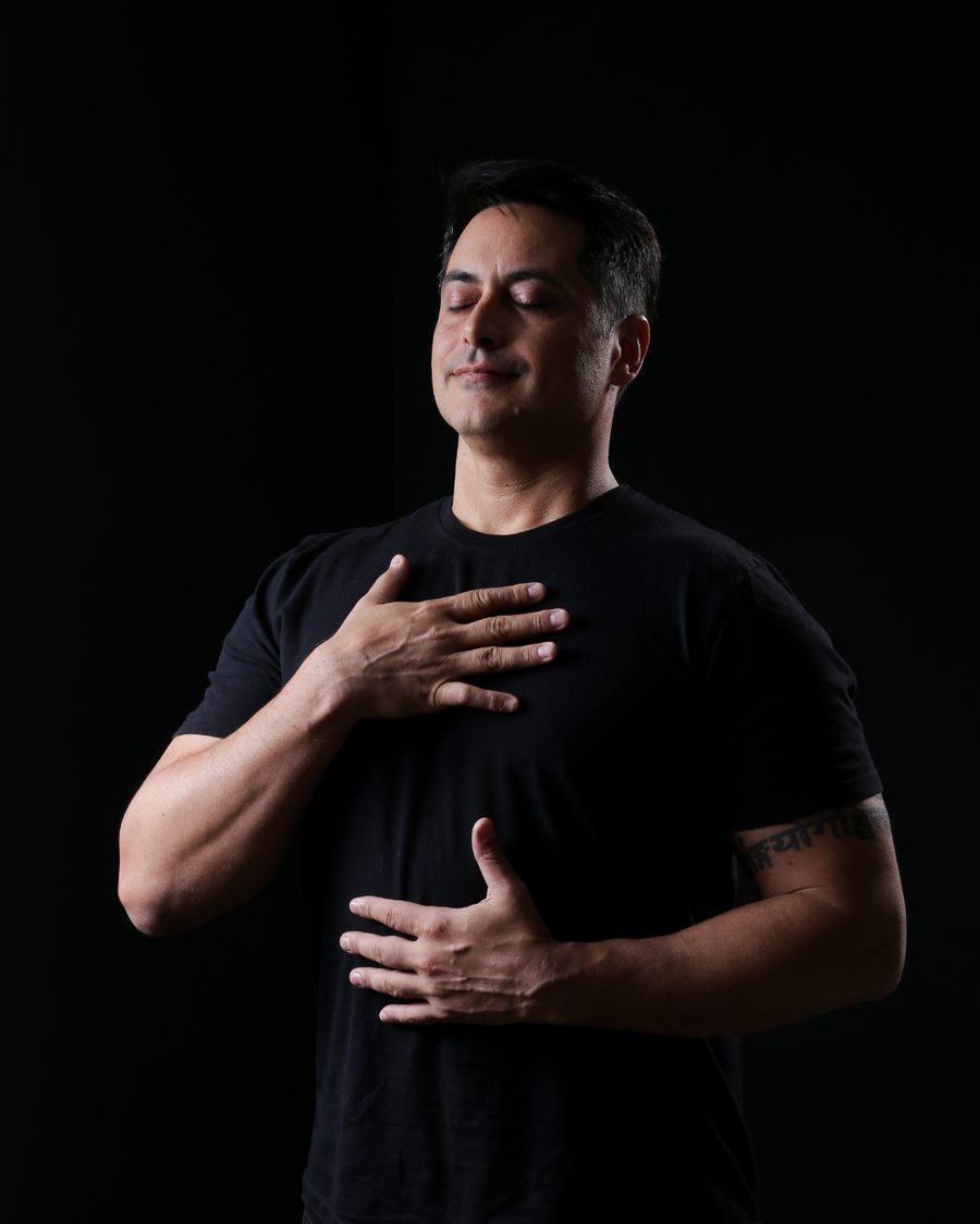 René Azzi de olhos fechados, com uma mão no peito e outra na barriga, respirando