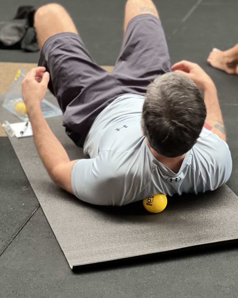 Participante deitado de costas sobre uma bola de liberação durante um workshop Recovery Trino